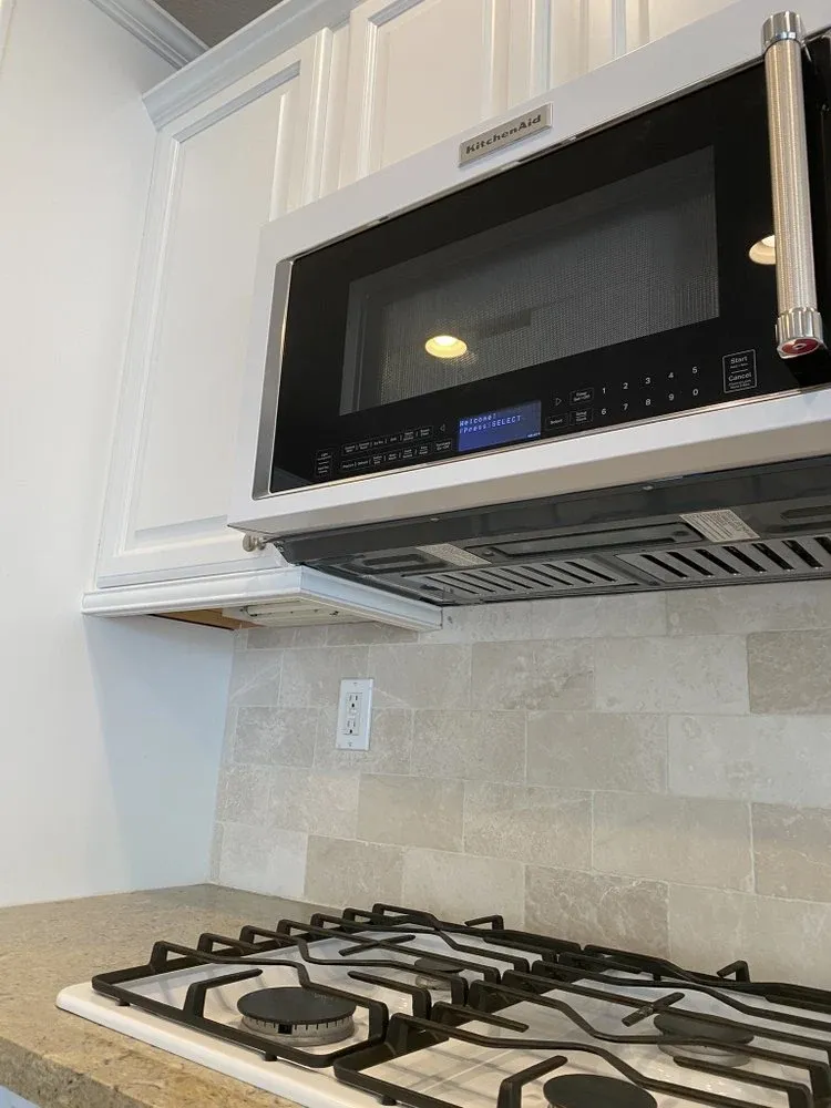 Over-the-range microwave installed above a new tile backsplash and gas cooktop