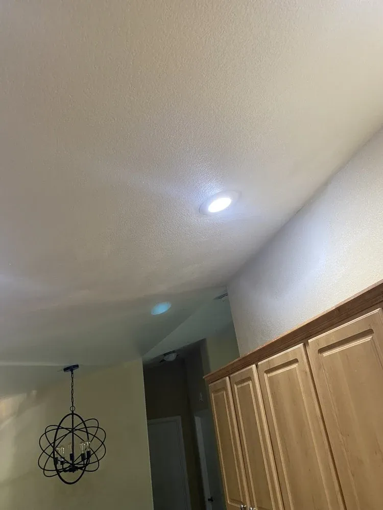 New recessed LED ceiling lights installed near a kitchen with an orb chandelier